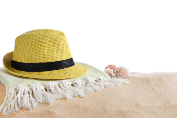 Складное полотенце, шляпа и раковины на песке на белом фоне, место для текста. Пляжные объекты - Фото, изображение