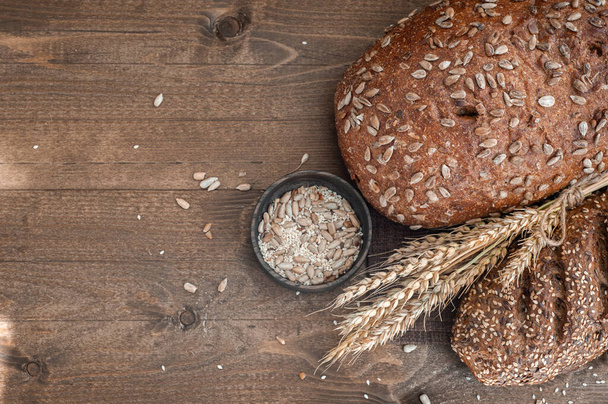 Different bread on a wooden background with wheat. - Fotó, kép