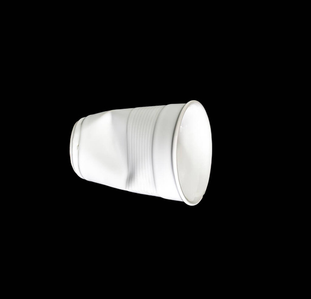 Crumpled white disposable paper plastic cup isolated on black background. - Photo, Image