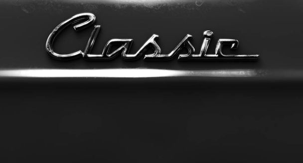 A closeup view of the word classic written as a chrome emblem in a retro font set on a car painted in reflective red paint - 3D render - Foto, Imagen