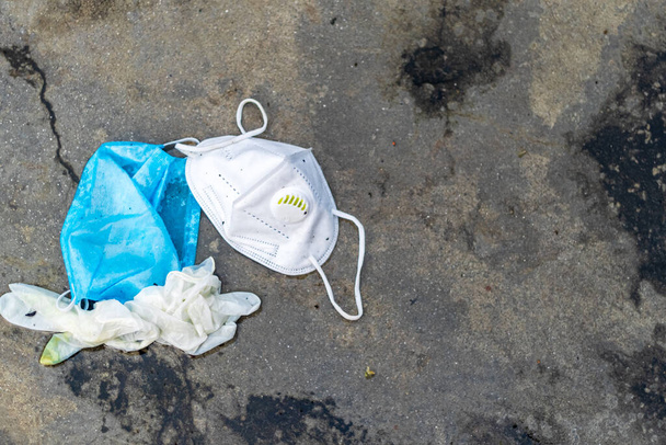COVID-19ゴミやゴミの概念。雨の屋外での使用後に捨てられた手袋、医療用フェイスマスク、 N95マスク. - 写真・画像