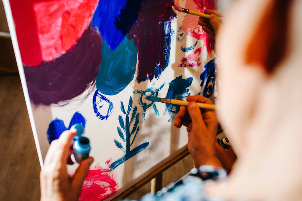 Kunstenaars handen met borstel en verf, verf op ezel, schilderen in het atelier. Kleurtekening, foto. Close-up kunst, creativiteit, mensbeeld. - Foto, afbeelding