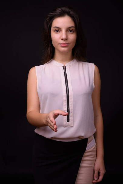 Studio shot of young beautiful businesswoman against black background - Zdjęcie, obraz