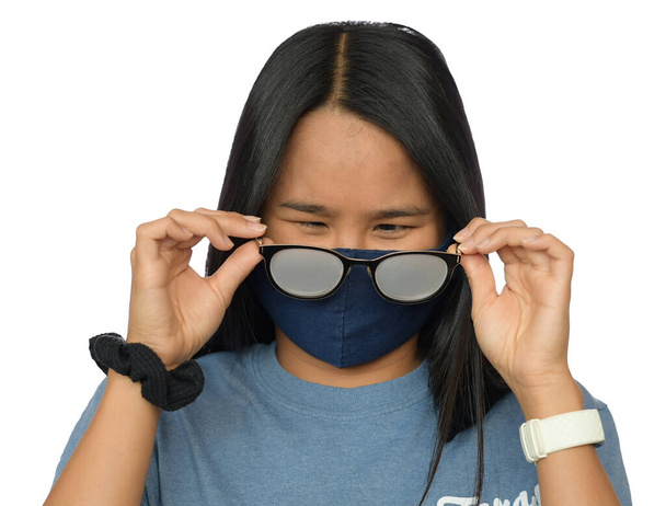 Χαριτωμένο κορίτσι από την Ασία με ομιχλώδη γυαλιά που προκαλείται από φορώντας μια προστατευτική μάσκα - Φωτογραφία, εικόνα