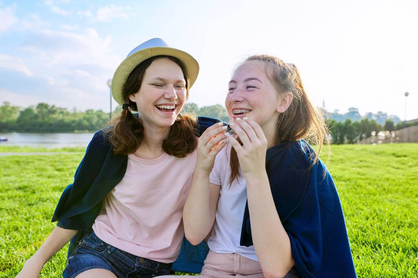 Girlfriends teenagers having fun sitting on grass on sunny summer day - Zdjęcie, obraz