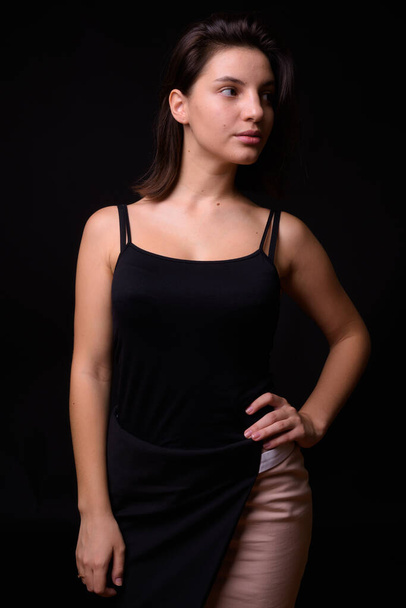 Studio shot of young beautiful woman against black background - 写真・画像