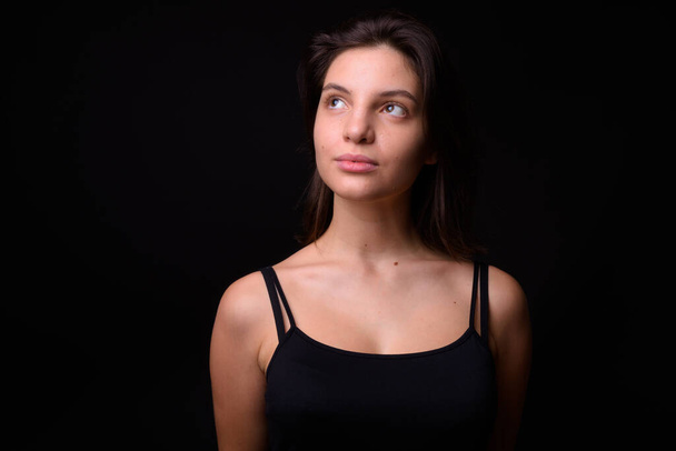Studio shot of young beautiful woman against black background - Фото, изображение