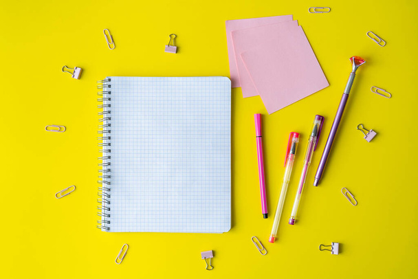 School supplies and a notebook lie on a yellow background. In the center, on a yellow surface, is a notebook, a place to copy space. Stationery, paper clips, post-it notes. Back to school. - 写真・画像