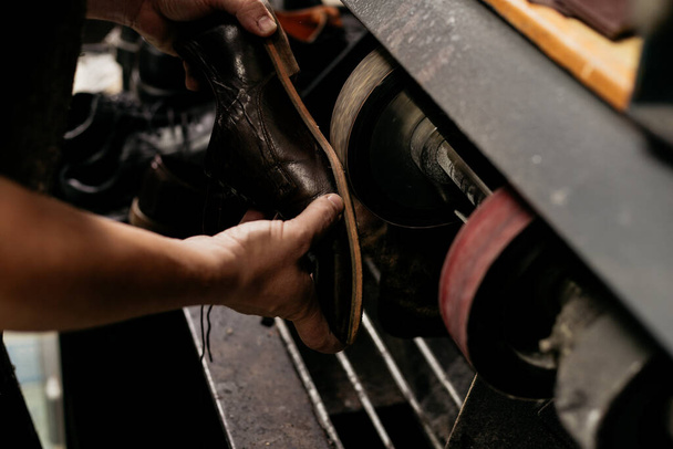 研削盤上の靴の靴底を修理男性靴屋。仕事中のコブラー.  - 写真・画像