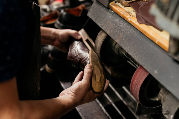 Erkek ayakkabıcı öğütme makinesinde ayakkabı tekerini tamir ediyor. Ayakkabı tamircisi..  - Fotoğraf, Görsel