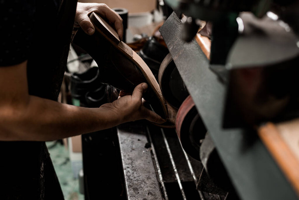 Egy férfi cipész cipőt javít a köszörűgépen. Csészealj munka közben.  - Fotó, kép