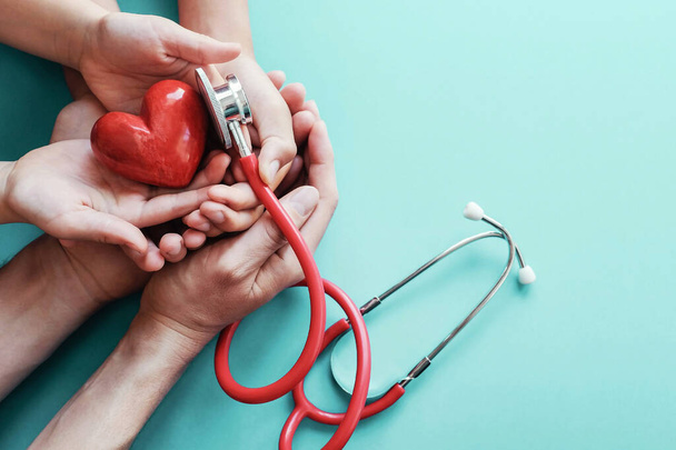 Mani di famiglia che tengono il cuore rosso con stetoscopio, salute cardiaca, concetto di assicurazione sanitaria, Giornata mondiale del cuore, Giornata mondiale della salute - Foto, immagini