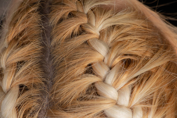 gevlochten spikelet op het hoofd van een jong blond meisje closeup - Foto, afbeelding