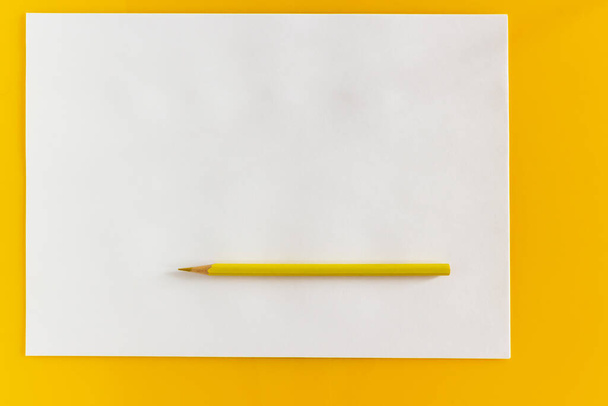 Yellow pencil and blank sheet of white paper on a yellow background - Fotoğraf, Görsel