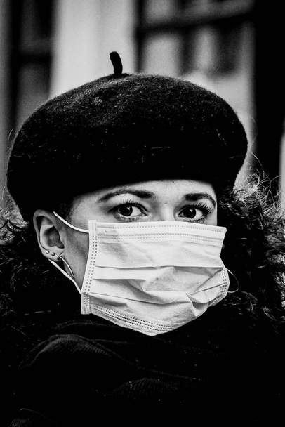 Schwarz-Weiß-Porträt der schönen jungen Europäerin mit medizinischer Gesichtsmaske zum Schutz gegen Covid19, Coronavirus - Foto, Bild