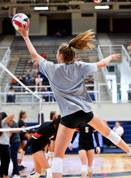 Молодая девушка делает удивительные игры во время игры в волейбол - Фото, изображение