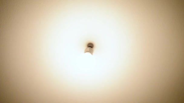 Lampadina senza lampada appesa al soffitto in movimento durante l'accensione e lo spegnimento. Illuminazione di una vecchia e cupa stanza. - Filmati, video
