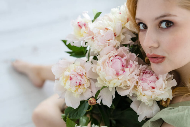 beautiful sensual girl with long blonde hair in dress with a bouquet of pink peonies flowers. oncept of feminity  - Fotó, kép