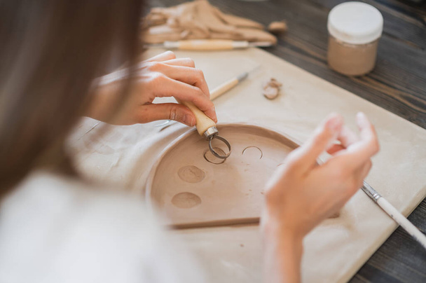 Professionale vasaio femminile sagomatura e intaglio parti laboratorio di ceramica, studio. Artigianato, opere d'arte e concetto artigianale. - Foto, immagini