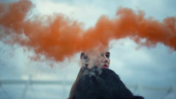 Egy lány füst bombával integet a kamera előtt. Fiatal nő pózol a kamera előtt - Felvétel, videó