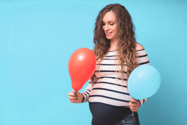Pregnant woman tries to guess the boy or girl. Balloons as symbol of boy and girl. Gender of the unborn child concept. Copy space. - Φωτογραφία, εικόνα