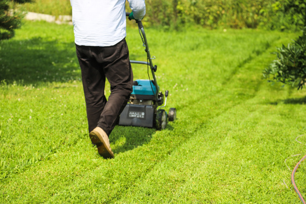 Un homme tond l'herbe sur son propre terrain de chalet - Photo, image