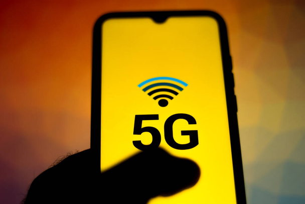 In this photo illustration the person surfs the mobile internet. The 5G inscription is displayed on the smartphone screen - Photo, Image