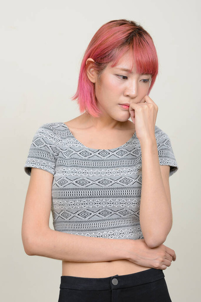 Studio shot of young beautiful Asian woman with pink hair against white background - Foto, immagini