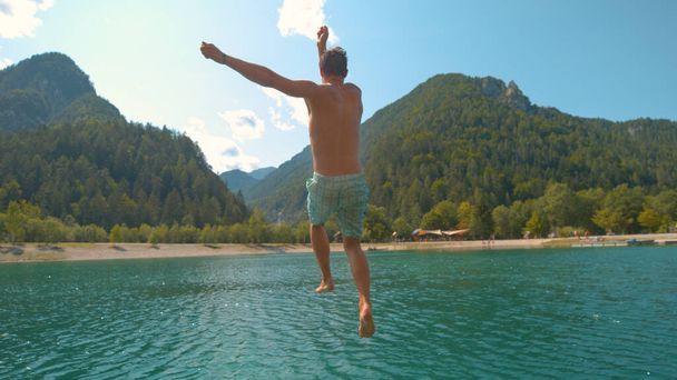 Близко: веселый кавказский турист ныряет в освежающее изумрудное озеро. - Фото, изображение