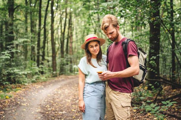 Couple using smart phone to navigate in woods. Theme tourism and navigation, search way, create route, gps phone app. Two people Hiking and Looking at Smartphone to Find the Way. - Photo, Image