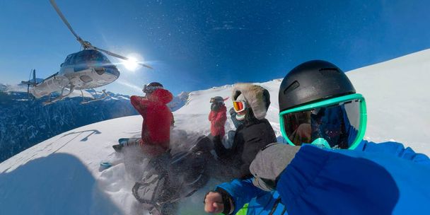 Grupa ekstremalnych snowboardzistów czeka, aż śmigłowiec ich odbierze. - Zdjęcie, obraz