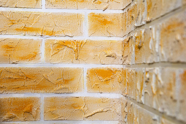 Vista de cerca de la esquina de la pared hecha de ladrillos de yeso hechos a mano. Patrón geométrico abstracto. Fondo naranja claro
 - Foto, imagen