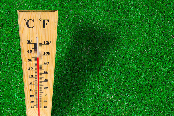 Mesure du thermomètre météo en bois sur une herbe verte pendant une journée chaude. - Photo, image