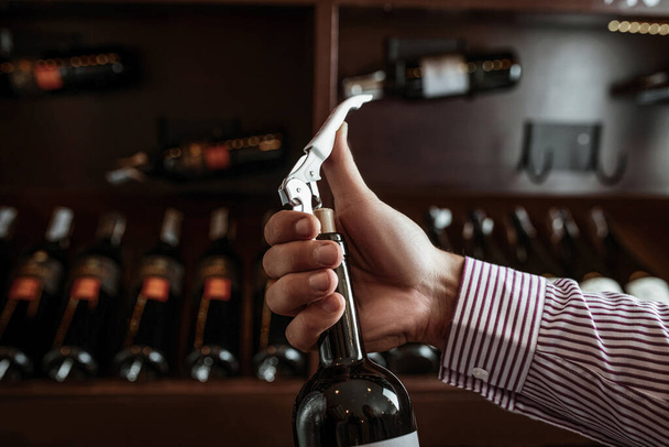 A professional sommelier demonstrates his skills by smelling a cork from a freshly opened wine drink. Sommelier. - Photo, Image