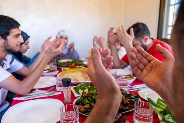 Familia árabe musulmana rezando por Dios antes de comer iftar - Foto, Imagen