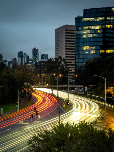 strepen van lichte paden van auto 's zoomen langs de st kilda kruising in Melbourne tijdens de spits - Foto, afbeelding