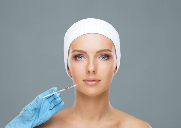 Doctor injecting in a beautiful face of a young woman. Plastic surgery, skin lifting and aesthetic medicine concept. - Foto, Imagen