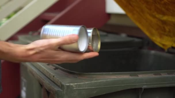 Persona pone latas de estaño en la papelera de reciclaje con tapa amarilla, primer plano
 - Metraje, vídeo