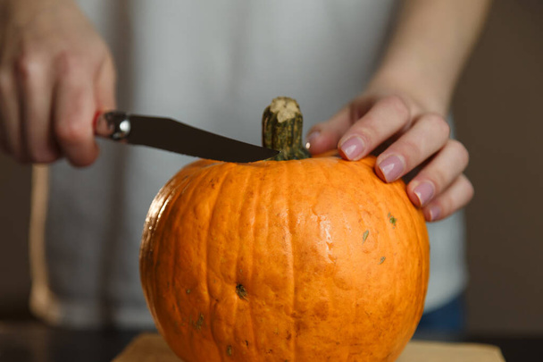 Female hands with knife chopping pumpkin on cutting board. Preparing autumn vegetables. Healthy organic vegetarian food concept.  - Foto, imagen