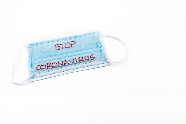 Single use medical face mask with handwritten message Stop Coronavirus isolated over white background, coronavirus protection concept - Photo, Image