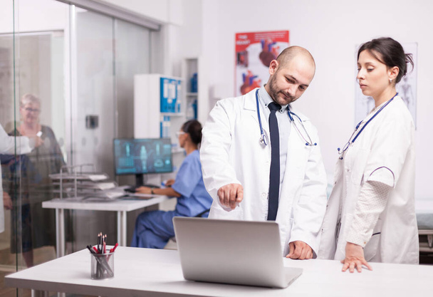 Młodzi lekarze wskazujący na ekran laptopa - Zdjęcie, obraz