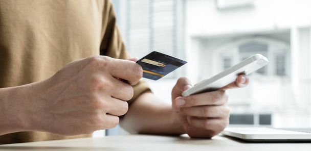 Az üzletember kezében van egy hitelkártya, és egy okostelefon az online vásárlás és az internetes fizetés az irodában. - Fotó, kép