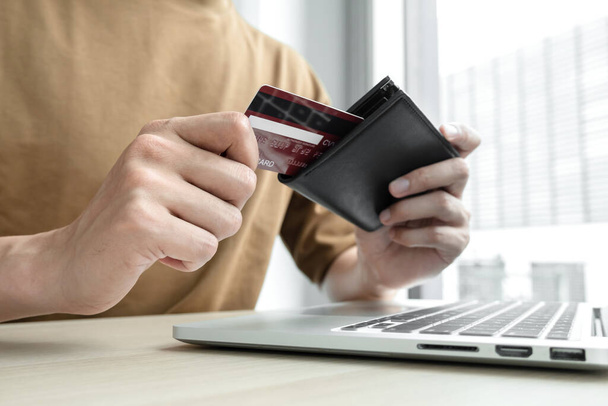 Die Hand des Geschäftsmannes hält eine Kreditkarte und benutzt einen Laptop für Online-Einkäufe und Internet-Zahlungen im Büro. - Foto, Bild