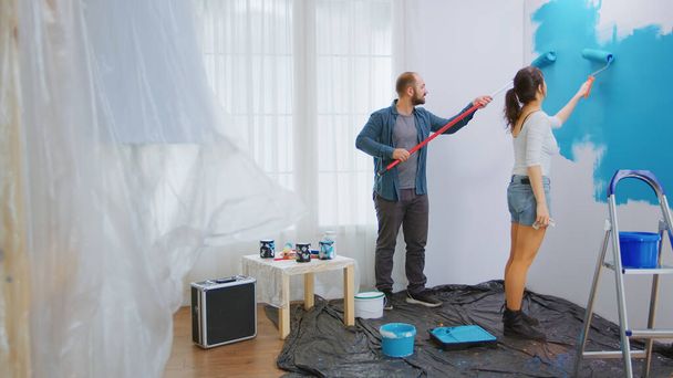Husband and wife painting wall - Фото, изображение