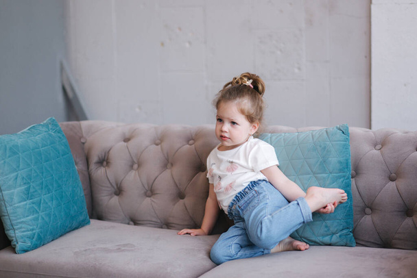 Portrait of beautiful little girl sits on sofa in studio - Foto, Bild