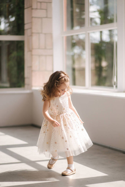 Cute little girl three year old in dress posing for photograper in studio. Beutiful little girl dance - Fotó, kép