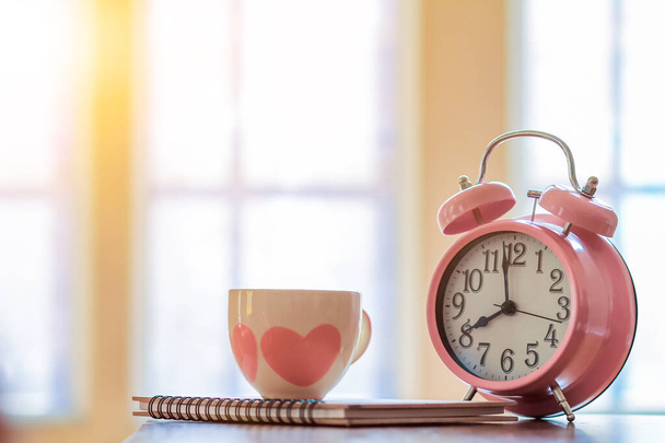 Gli orologi sveglia e le tazze da caffè sono posizionati su un tavolo di legno vicino alla finestra al mattino per prepararsi a lavorare a casa per aiutare a ridurre la diffusione del coronavirus covid-19. Il concetto di lavoro da casa - Foto, immagini