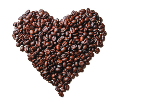 黒焙煎したコーヒー豆は、愛、友情、優しさの象徴を示すために心臓の形で白い背景に配置されています。コーヒー豆との友情と愛を象徴するコンセプト - 写真・画像