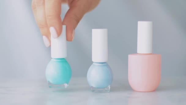 Pastelowa scena kosmetyczna, kobiece dłonie i butelki do manicure francuskiego, kolorowy pastelowy lakier do paznokci na marmurowym stole, makijaż i marka kosmetyczna - Materiał filmowy, wideo