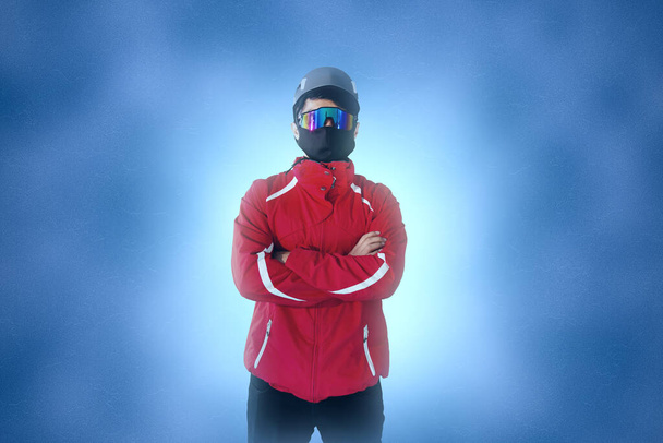 full length portrait of hiker with mask, glasses, helmet and boots on blue background - Foto, afbeelding
